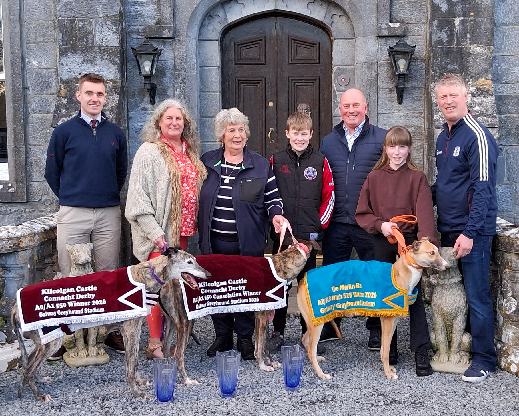 Connections of the 2026 Kilcolgan Castle Connacht Derby winners pictured at Kilcolgan Castle with their greyhounds following success at Galway Greyhound Stadium, proudly displaying their winner and consolation trophies.