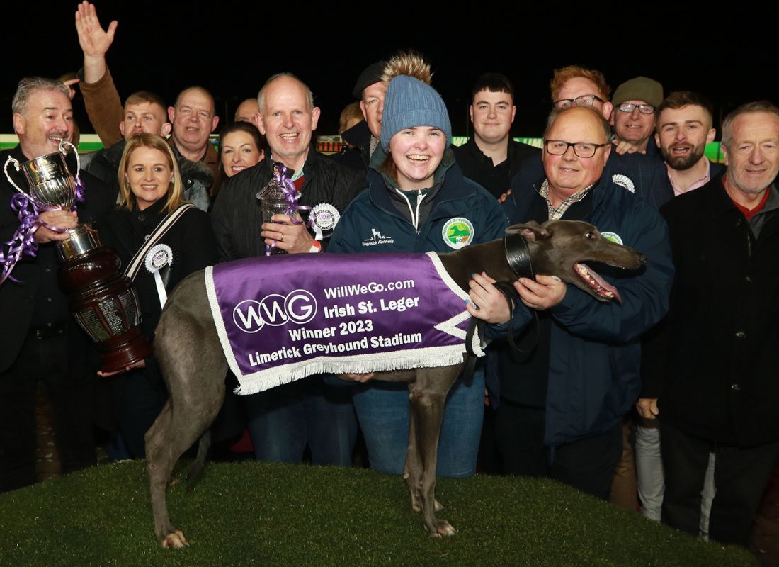 Image shows a closer shot of part of a large group of people at the winner's podium of Limerick Greyhound Stadium for the presentation by WillWeGo.com's Ray Quinn to winning owners James and Muireann Murphy, trainer Graham Holland, Breeder Jerry Murphy and winning greyhound Clonbrien Treaty. The group includes a number of people including the Mayor of Limerick and TD's and Councillors and connections of the 2023 WillWeGo.com Irish St Leger Final 
