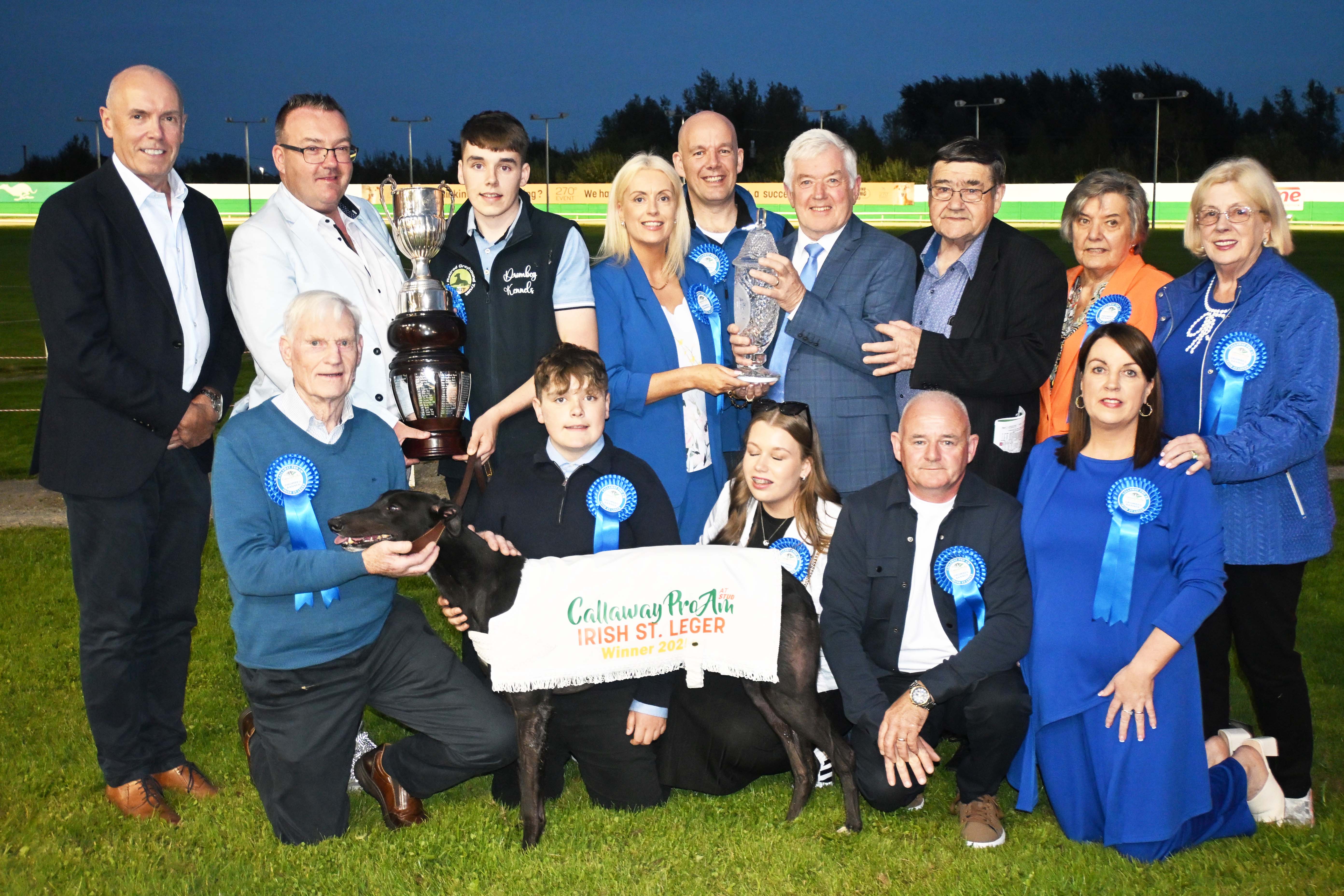 Sponsor Denis Murphy presents the trophy to 18 year old Evan McAuliffe after he and Drombeg Banner won the 2025 Callaway Pro Am At Stud Irish St. Leger Final at Limerick Greyhound Stadium Image shows a group of people and a greyhound at the winner's presentation for the 2025 Callaway Pro Am At Stud Irish St. Leger at Limerick Greyhound Stadium